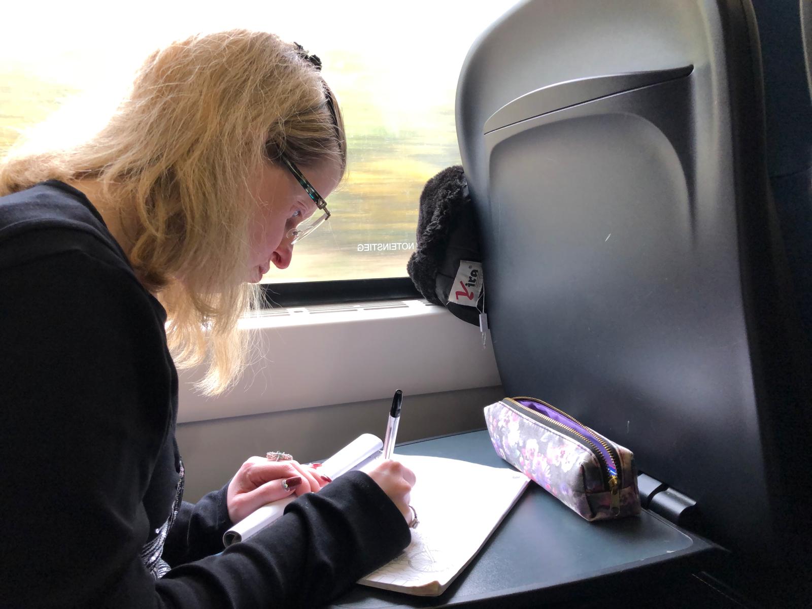 Jen Blackwell writing in notebook on a train