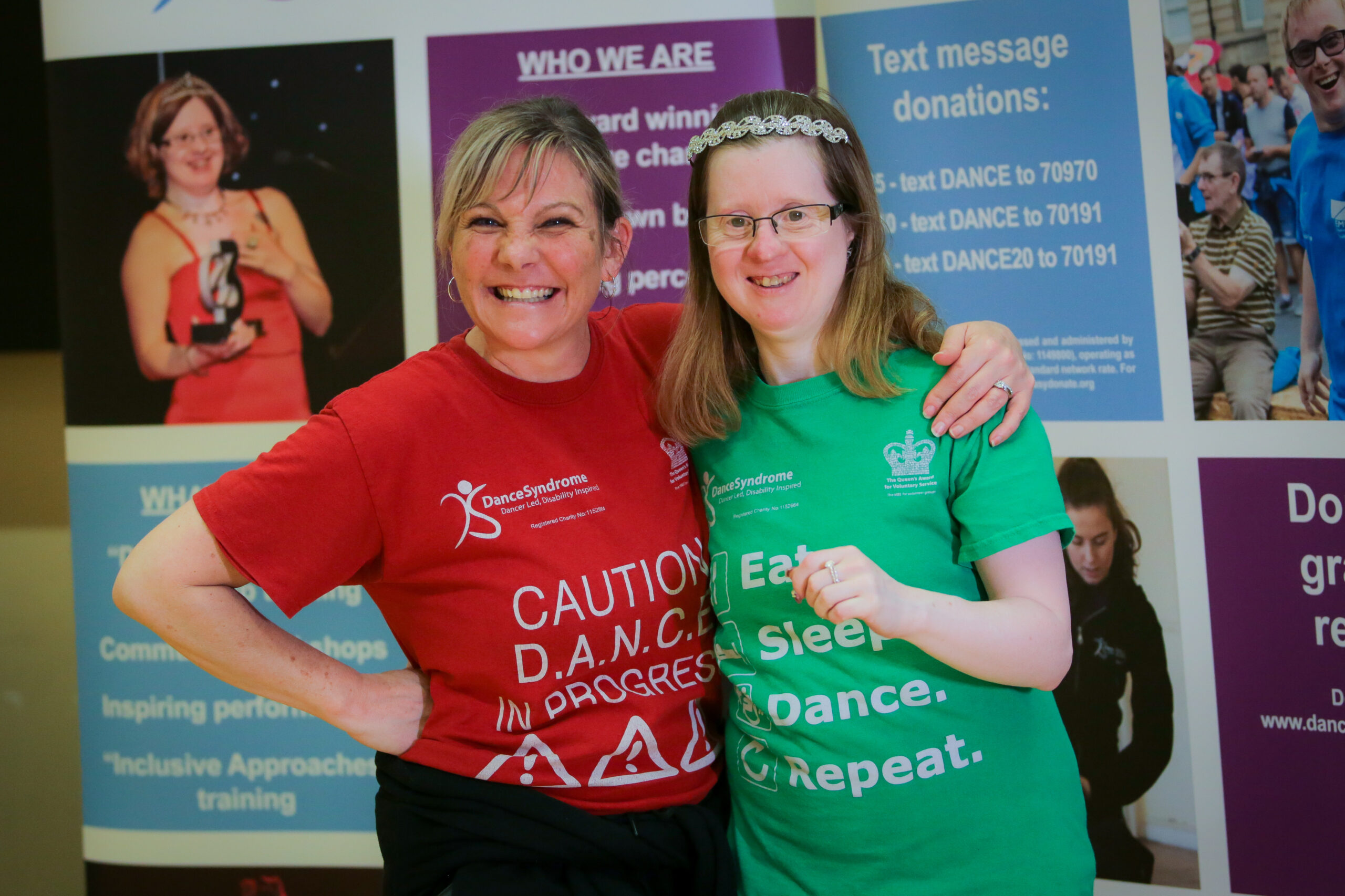 Two women smiling together with arms around each other having fun.
