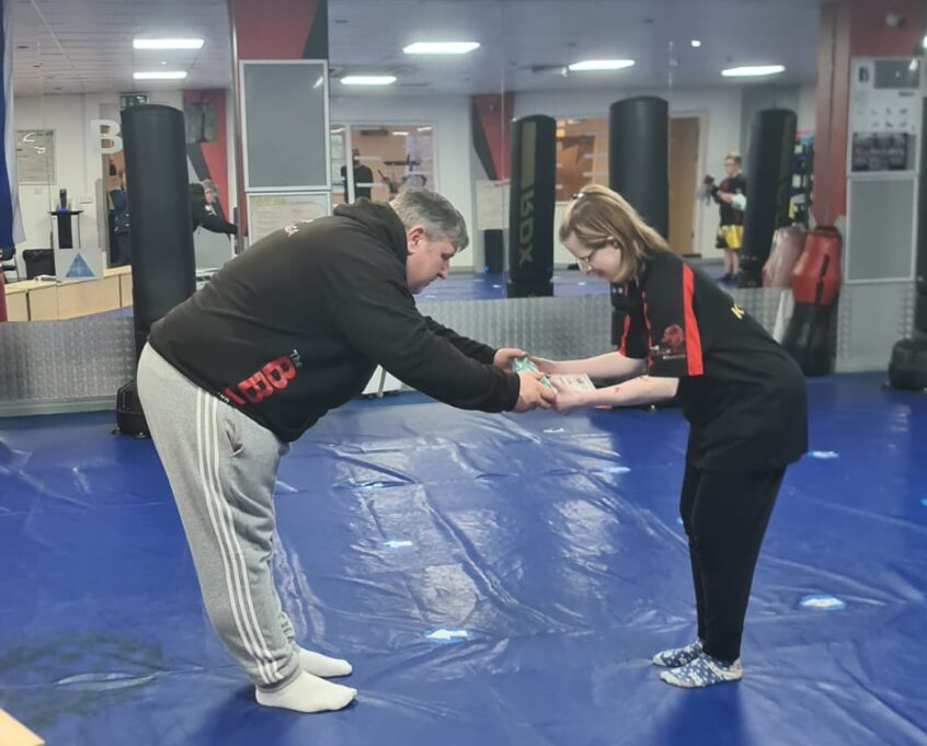 Jen bowing down receiving her green belt from bowing down instructor in Krave