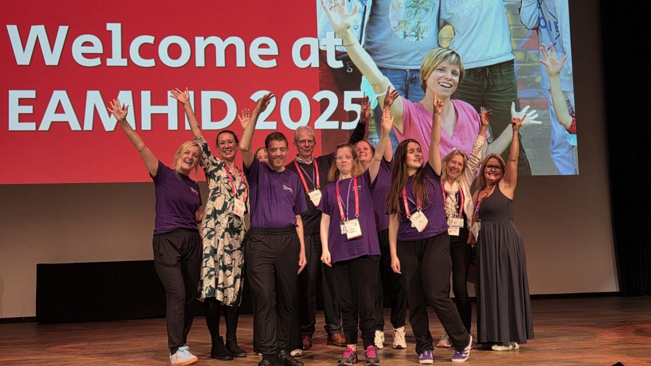 Group of people on stage smiling and waving arms in air