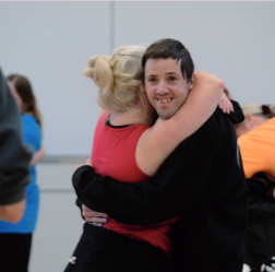 Two people embracing. Man with short dark hair smiling at the camera