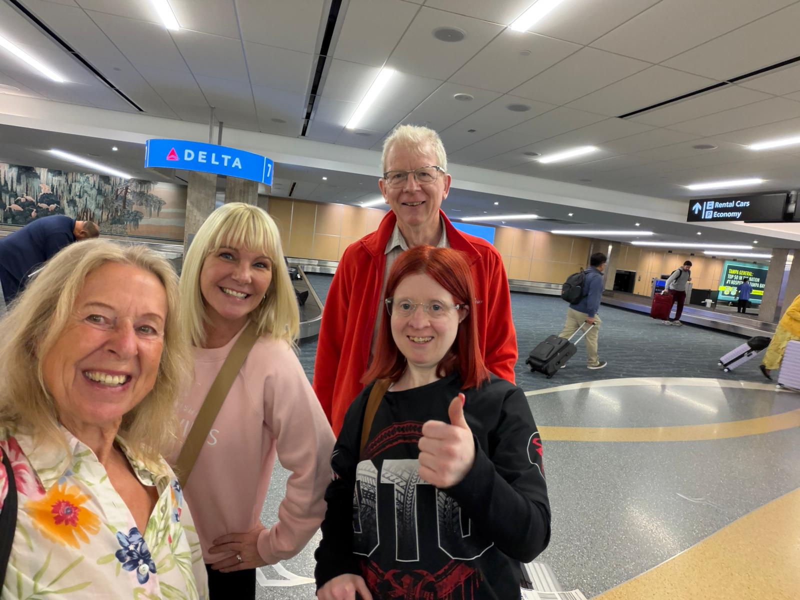 four people together at an airport looking happy