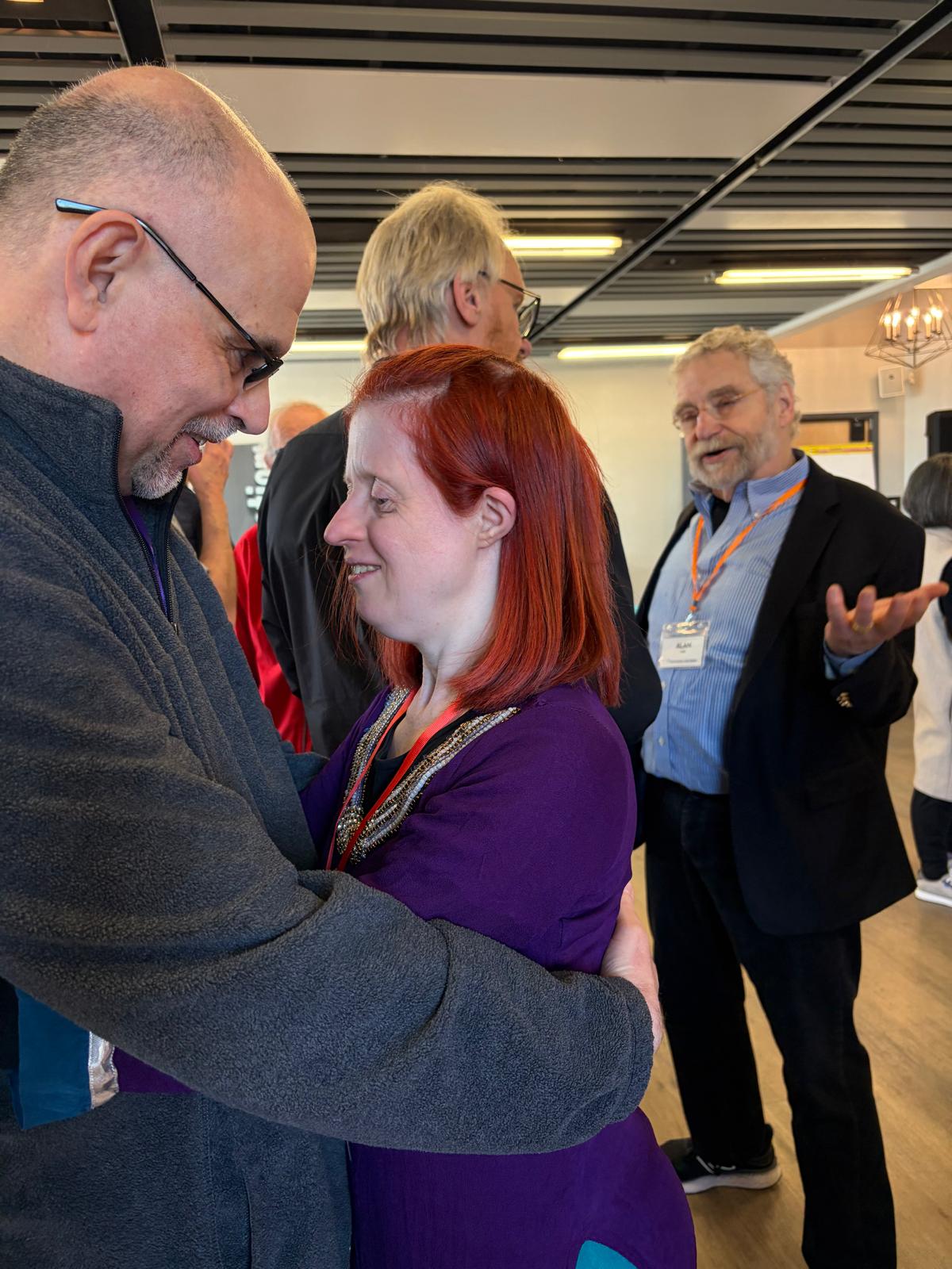Man wearing glasses looking at woman in a loose embrace
