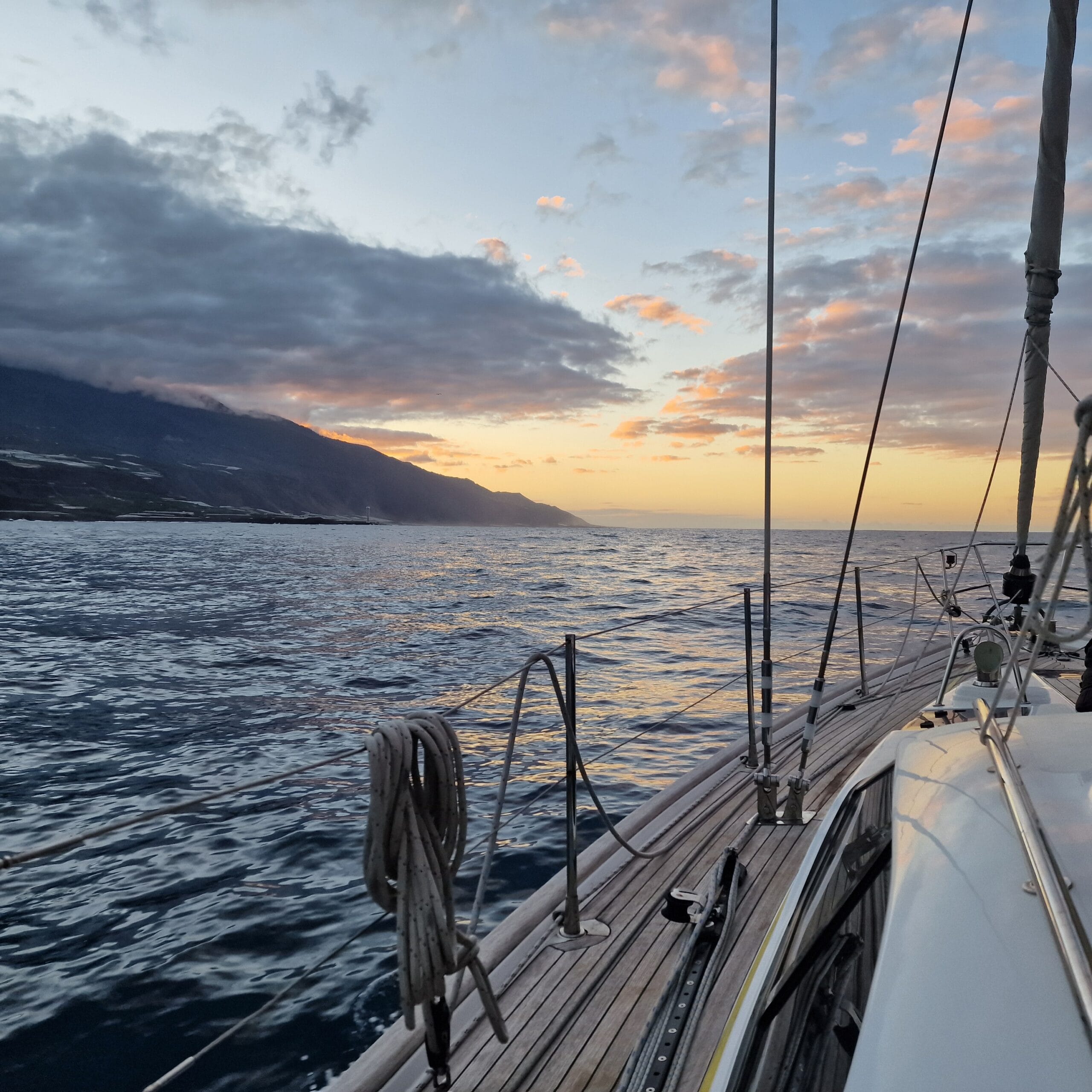 Sunrise over headland from yacht sailing on ocean