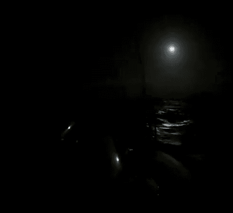 Dark sky over sea with moon lighting tops of waves