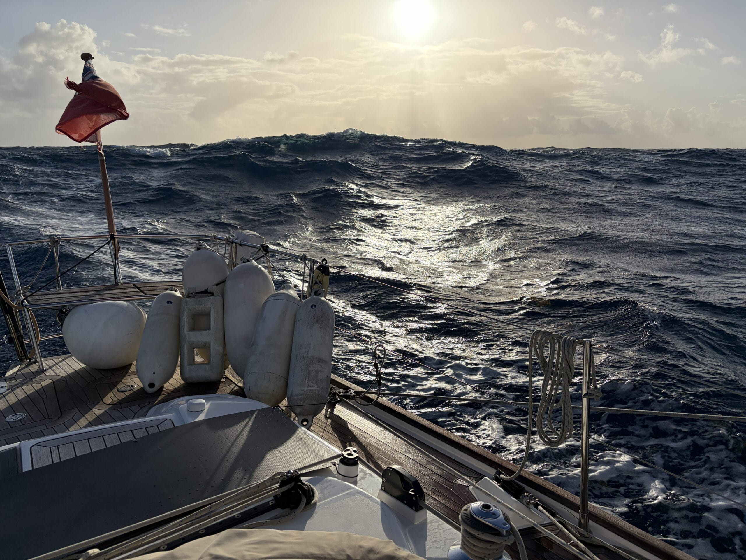 Looking to setting sun from back of yacht with waves rolling towards boat